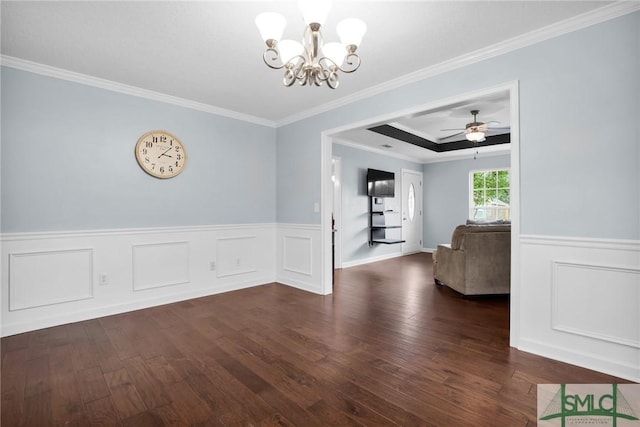 unfurnished dining area featuring crown molding, ceiling fan with notable chandelier, wood finished floors, and a wainscoted wall