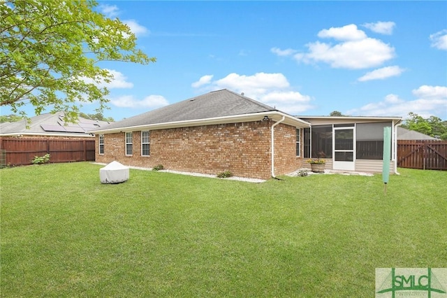 back of house featuring a fenced backyard, a lawn, and a sunroom