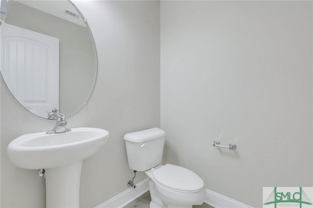 bathroom featuring baseboards, toilet, and visible vents