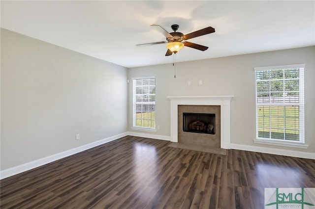 unfurnished living room with baseboards, a ceiling fan, dark wood-style flooring, and a wealth of natural light