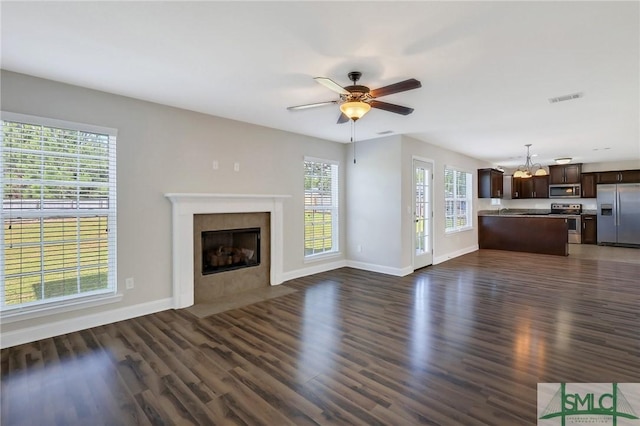unfurnished living room featuring visible vents, baseboards, dark wood-style flooring, and a tiled fireplace