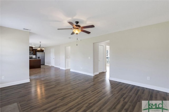 unfurnished living room with baseboards, ceiling fan with notable chandelier, dark wood finished floors, and visible vents