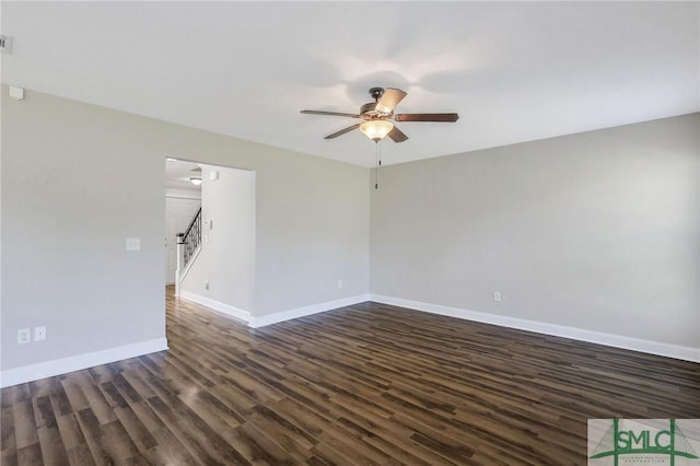 unfurnished room with stairs, a ceiling fan, baseboards, and dark wood finished floors