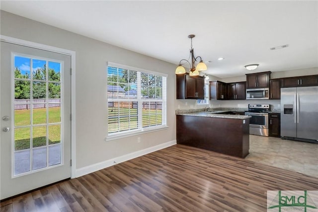kitchen with visible vents, wood finished floors, dark brown cabinets, baseboards, and stainless steel appliances