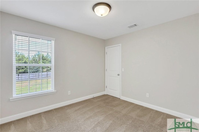 unfurnished room featuring a healthy amount of sunlight, carpet floors, baseboards, and visible vents
