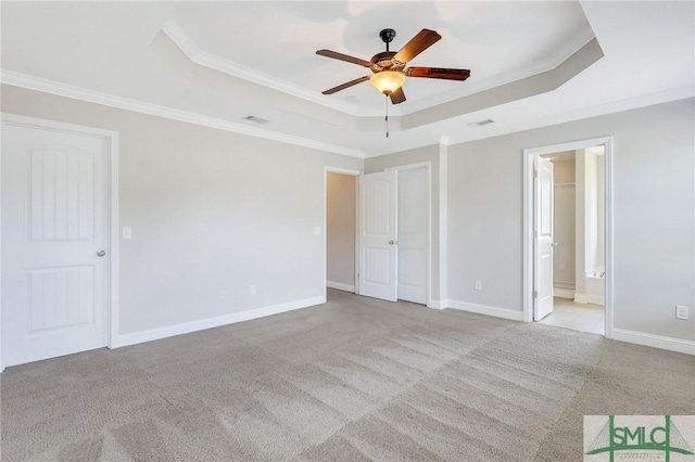 unfurnished bedroom featuring crown molding, a tray ceiling, visible vents, and carpet floors