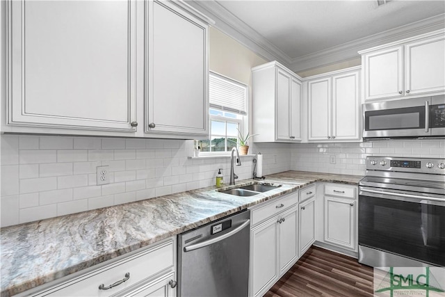 kitchen with light stone countertops, a sink, white cabinets, ornamental molding, and stainless steel appliances