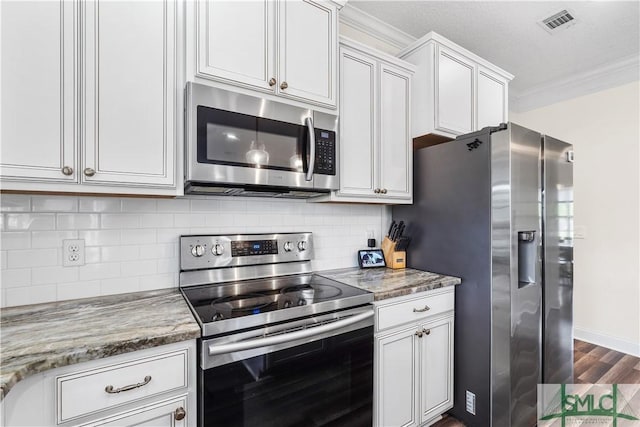 kitchen with appliances with stainless steel finishes, ornamental molding, backsplash, and visible vents