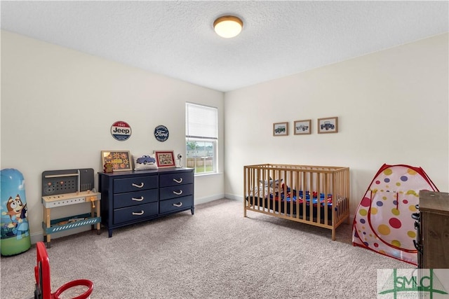 bedroom with carpet flooring, a textured ceiling, a crib, and baseboards