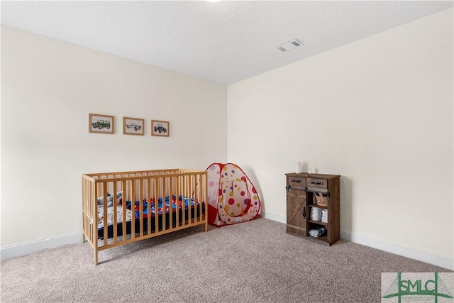 bedroom with baseboards, a crib, carpet flooring, and visible vents