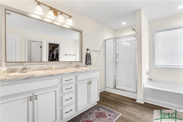 bathroom featuring wood finished floors, a sink, and a stall shower