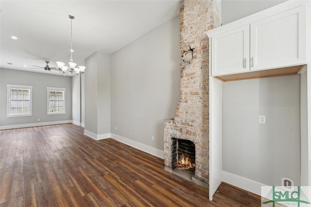 537 E Congress St, Savannah, GA 31401 - unfurnished living room featuring baseboards, dark wood-style floors, ceiling fan with notable chandelier, and a fireplace