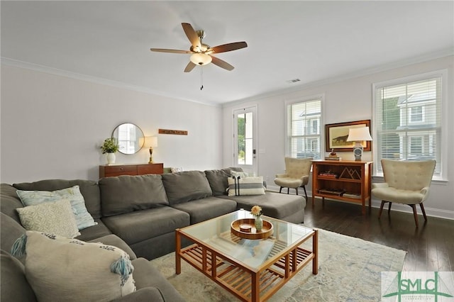 living area with ceiling fan, baseboards, wood finished floors, visible vents, and ornamental molding