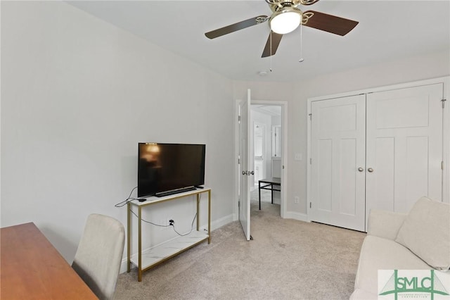 living room with baseboards, a ceiling fan, and carpet