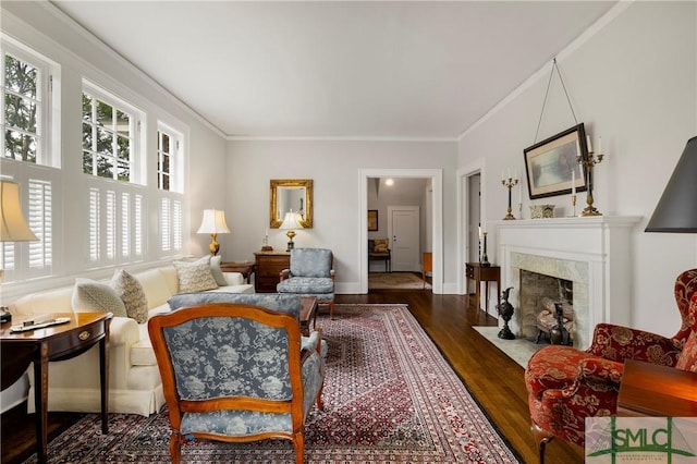 living area featuring a premium fireplace, baseboards, ornamental molding, and wood finished floors