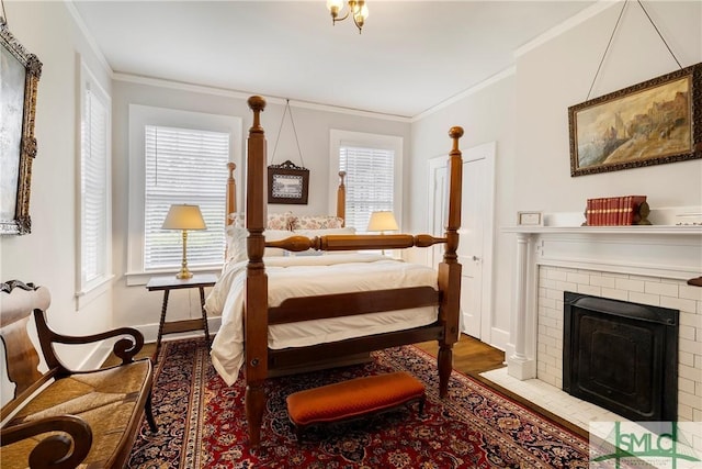 bedroom featuring crown molding, baseboards, a brick fireplace, and wood finished floors