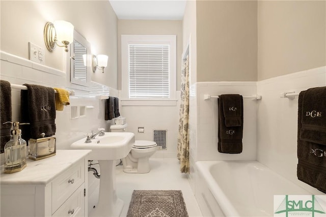 bathroom featuring visible vents, wainscoting, toilet, a shower with shower curtain, and a tub to relax in