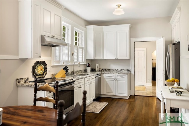 kitchen with under cabinet range hood, white cabinets, appliances with stainless steel finishes, and a sink