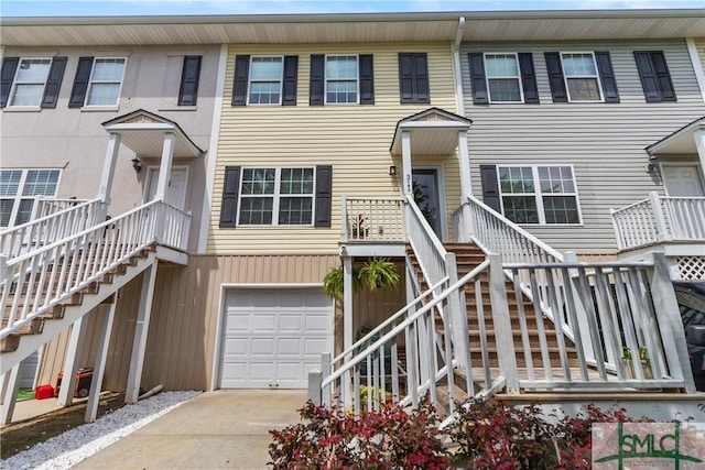 view of property with stairs, an attached garage, and concrete driveway