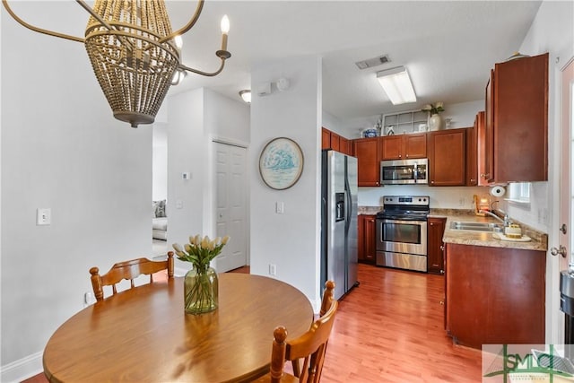 kitchen featuring visible vents, appliances with stainless steel finishes, light wood-type flooring, a sink, and light countertops