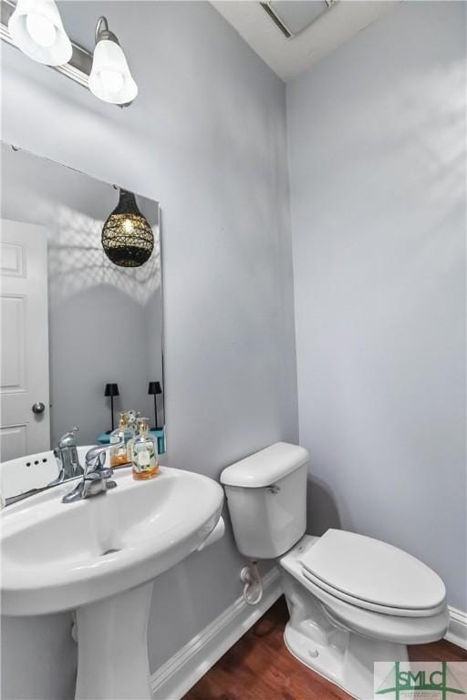 half bathroom featuring toilet, baseboards, visible vents, and wood finished floors
