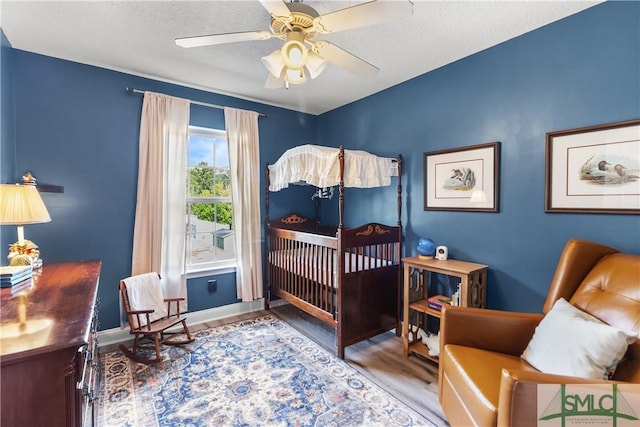 bedroom with a textured ceiling, baseboards, ceiling fan, and wood finished floors