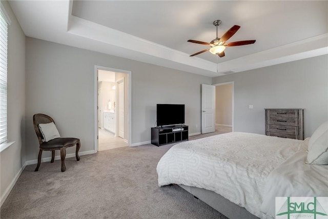 carpeted bedroom with baseboards, ceiling fan, a tray ceiling, and ensuite bathroom