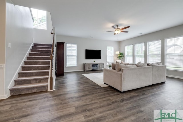 living area with stairway, plenty of natural light, dark wood-style flooring, and ceiling fan
