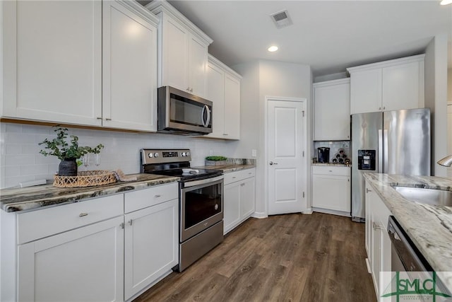 kitchen with white cabinets, dark wood-style flooring, light stone countertops, appliances with stainless steel finishes, and visible vents