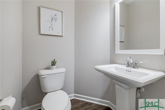 half bath featuring baseboards, toilet, and wood finished floors
