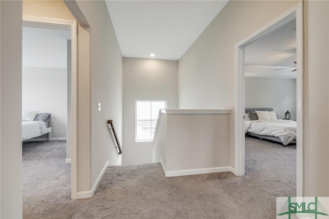 hallway featuring baseboards, an upstairs landing, and carpet