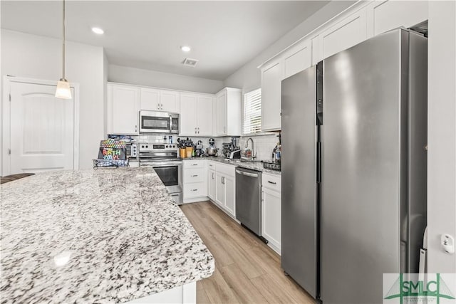 227 Flagler Dr, Savannah, GA 31419 - kitchen with visible vents, light wood-style floors, white cabinetry, a sink, and stainless steel appliances