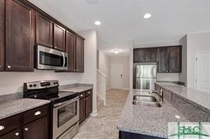 kitchen featuring a sink, appliances with stainless steel finishes, a kitchen island with sink, and dark brown cabinets