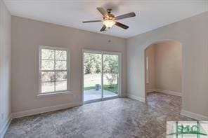 empty room with arched walkways, baseboards, and ceiling fan