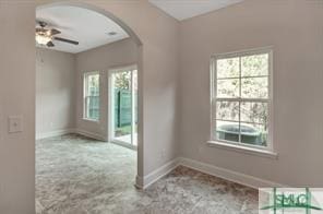 unfurnished room with arched walkways, baseboards, and a ceiling fan