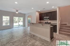kitchen featuring arched walkways, stainless steel microwave, recessed lighting, and open floor plan