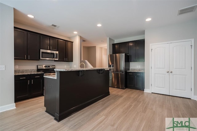 270 Kepler Loop, Richmond Hill, GA 31324 - kitchen with stainless steel appliances, light wood-style floors, light stone counters, a kitchen breakfast bar, and a center island with sink