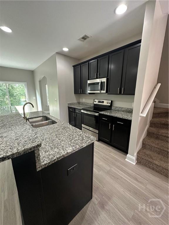 270 Kepler Loop, Richmond Hill, GA 31324 - kitchen with stainless steel appliances, a sink, dark cabinetry, light stone counters, and arched walkways