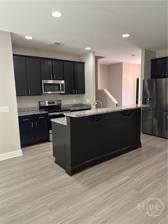270 Kepler Loop, Richmond Hill, GA 31324 - kitchen with stainless steel appliances, dark cabinetry, a kitchen bar, light wood finished floors, and recessed lighting