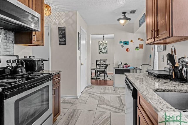 kitchen with visible vents, marble finish floor, brown cabinets, light stone counters, and appliances with stainless steel finishes