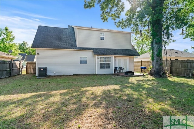 rear view of property with french doors, central air condition unit, a lawn, and a fenced backyard