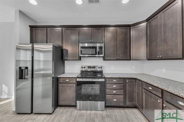 95 Wando View Way, Richmond Hill, GA 31324 - kitchen featuring dark brown cabinets, appliances with stainless steel finishes, light stone counters, light wood finished floors, and recessed lighting