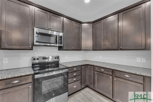 95 Wando View Way, Richmond Hill, GA 31324 - kitchen with dark brown cabinetry, appliances with stainless steel finishes, light wood finished floors, and light stone countertops