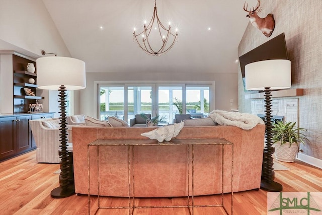 living area with a notable chandelier, high vaulted ceiling, and light wood-style floors