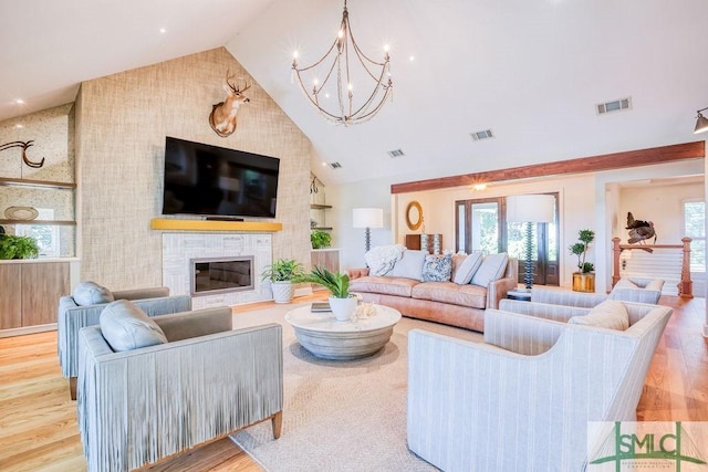 living area with visible vents, a chandelier, high vaulted ceiling, and wood finished floors