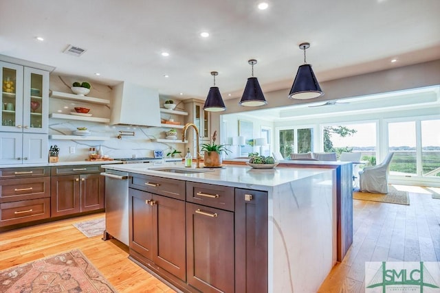 kitchen with light wood-style flooring, stainless steel dishwasher, visible vents, a sink, and open shelves