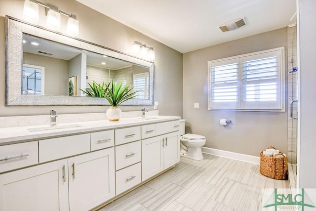 bathroom with double vanity, visible vents, baseboards, and a sink