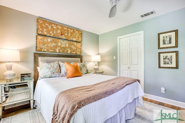 bedroom with wood finished floors, a ceiling fan, a closet, visible vents, and baseboards