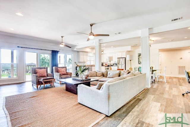 living room with ornate columns, a ceiling fan, visible vents, and light wood-style floors