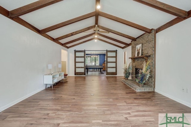 unfurnished living room with baseboards, lofted ceiling with beams, a ceiling fan, and wood finished floors
